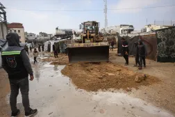 جرافة تحاول تجفيف شارع غمرته المياه في مخيم مؤقت يؤوي نازحين فلسطينيين بخان يونس (أ.ف.ب)