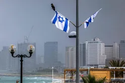 A crow perches on an Israeli flag near an empty beach along the Tel Aviv coastline on April 7, 2026. (AFP)