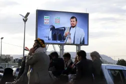 أشخاص يستقلون سيارة في صنعاء تمر أمام لوحة إعلانية رقمية تحمل صورة زعيم الحوثيين يوم 9 أبريل 2026 (إ.ب.أ)