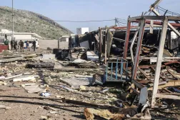 Komala party members look towards the debris is strewn from mangled structures following drone strikes on the Iranian Kurdish opposition Komala party's Sordash camp, which resulted in the death of a female party member and the injury of two others, some 40 km northwest of the city of Sulaymaniyah in the autonomous Kurdistan region on April 15, 2026. (AFP)