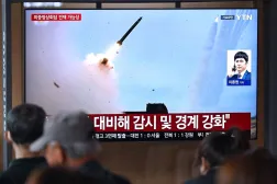 People watch a television screen showing a news broadcast with file footage of a North Korean missile test, at a train station in Seoul on April 19, 2026. (AFP)
