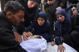 Mourners weep beside the body of a child at a hospital in Gaza City (AFP)