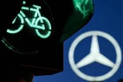 A traffic light for cyclists is pictured in front of a giant logo of German automotive brand Mercedes-Benz is seen atop a Mercedes dealership in Offenbach, western Germany, on April 29, 2026. (AFP)