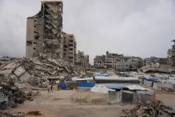 فلسطينيون يسيرون وسط مبانٍ مدمرة في مدينة غزة (أ.ب)