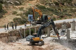İsrail askerleri işgal altındaki Batı Şeria'da, Ramallah yakınlarındaki köyde bir binayı yıkarken yolu kapatıyor (20 Mayıs, AFP)