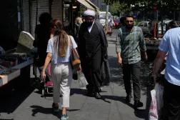 A cleric walks among other people on a sidewalk at the Revolution square in Tehran, Iran, Monday, June 8, 2026 (AP)