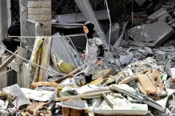 Lübnan’ın güneyindeki Nebatiye el-Fevka beldesinde yıkılan evlerin arasında yürüyen bir kadın. (AFP)