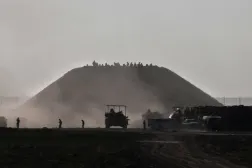 İsrail’e ait bir askeri nakliye aracı Gazze'den ayrılırken, askerler Gazze Şeridi sınırındaki bir tepenin yakınlarında toplanıyor (AFP)