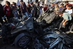 Filistinliler, İsrail'in Gazze kentinde bir aracı hedef aldığı hava saldırısının ardından olay yerini inceledi. (Reuters)