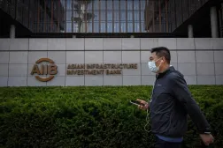 Pekin’deki Asya Altyapı Yatırım Bankası (AIIB) binasının önünden geçen bir adam (AFP)