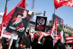 امرأة تحمل لافتة مناهضة للرئيس الأميركي دونالد ترمب بينما يتجمّع المشيّعون في يوم دفن المرشد الإيراني علي خامنئي... في مشهد بإيران يوم 9 يوليو 2026 (رويترز)