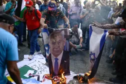 Göstericiler, ABD Başkanı Donald Trump ve İsrail Başbakanı Binyamin Netanyahu'nun fotoğraflarını yakarken (AFP)