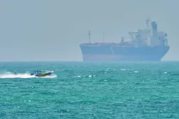 Hürmüz Boğazı’nda bulunan Keşm Adası açıklarında bir kargo gemisinin yanından geçen bir sürat teknesi (AP)