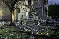 Kurtarma görevlisi, Rusya'nın Ukrayna'ya yönelik saldırısı sırasında Kiev'de Rus füze saldırılarıyla hasar gören bir apartman binasının enkazı arasında yürüyor (Reuters)