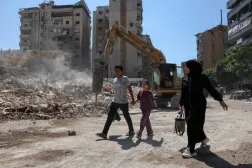 Beyrut’un güney banliyösünde yaşayanlar, İsrail saldırıları sonucu yıkılan binaların yanından geçiyor (Reuters)