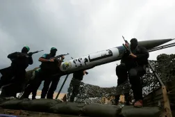 Hamas militanları, 14 Aralık 2014'te Gazze Şeridi'nde hareketin kuruluşunun 27. yıldönümü kutlamaları sırasında yerel yapım bir Kassam roketinin sergiliyor (Reuters)