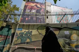 إيرانية تسير أمام لوحة في طهران تحمل صور خليل الحية زعيم «حماس» الحالي مع إسماعيل هنية ويحيى السنوار زعيمي الحركة السابقين اللذين قتلتهما إسرائيل (أ.ب)