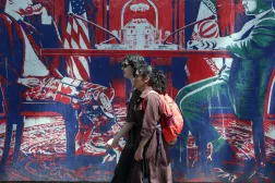 إيرانيتان تمران أمام جدارية مناهضة لأميركا قرب السفارة الأميركية السابقة في طهران الاثنين (إ.ب.أ)