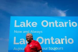 Ontario Başbakanı Doug Ford, Kanada kıyısında devasa bir reklam panosu büyüklüğündeki "Ontario Gölü. Şimdi ve sonsuza dek" yazılı tabelanın önünde, (AP)