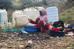 يمنية في تعز تغسل الملابس في مخيم مؤقت للنازحين جراء التصعيد الحوثي (رويترز)