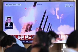 People sit near a television screen showing a news broadcast with file footage of a North Korean missile test, at a train station in Seoul on September 20, 2026. (Photo by Lillian SUWANRUMPHA / AFP)
