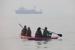 Women use paddleboards, as a vessel in the Strait of Hormuz appears in the distance, near the beach of Bandar Abbas, Iran, October 6, 2026. Amirhosein Khorgooi/ISNA/via WANA (West Asia News Agency) via REUTERS 