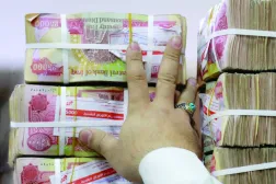 موظف يرتب أكواماً من الدينار العراقي في محل صرافة ببغداد (أ.ف.ب)