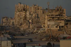 İsrail ile Hamas arasındaki savaş sırasında İsrail’in askeri saldırıları sonucu yıkılan binalarla çevrili bir caddede yürüyen Filistinliler, 8 Ekim 2026, Gazze (AP)
