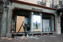 رجل يصلح نافذة متجر «سالومون» (Salomon) تضرر خلال اشتباكات وقعت في اليوم التالي لمظاهرات وطنية احتجاجاً على غلاء المعيشة وارتفاع أسعار الوقود في باريس (رويترز)