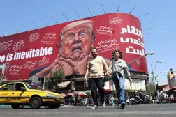 إيرانيون يمرون قرب لوحة مناهضة للرئيس الأميركي دونالد ترمب في طهران الخميس (إ.ب.أ)
