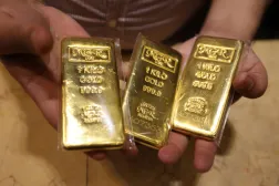 بائع يعرض سبائك ذهبية في متجر مجوهرات داخل سوق الذهب في السوق القديمة بدبي (إ.ب.أ)