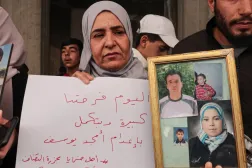 سورية تحمل صور أقارب لها خلال أبريل الماضي كانوا قتلوا في «مجزرة التضامن» جنوب دمشق (إ.ب.أ)