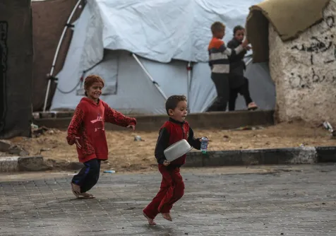 أطفال فلسطينيون يلعبون خارج مخيم في مدينة غزة (إ.ب.أ)