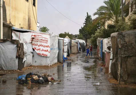 أطفال فلسطينيون يمشون بين الخيام بعد هطول الأمطار على قطاع غزة (أ.ب)