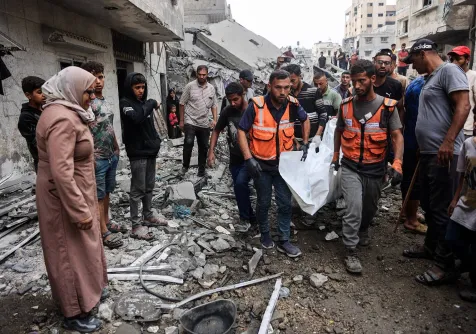 فلسطينيون يحملون جثثاً انتشلوها من بين أنقاض منزل دمر في غارة إسرائيلية بمدينة غزة (أ.ف.ب)