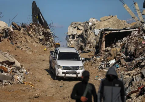 مقاتلون من «كتائب القسام» الجناح العسكري لحركة «حماس» يقفون حراساً أثناء البحث عن جثث رهائن إسرائيليين إلى جانب عمال الصليب الأحمر وسط أنقاض مخيم جباليا للاجئين شمال قطاع غزة يوم 1 ديسمبر 2025 (إ.ب.أ)