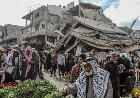 فلسطينيون يتسوقون وسط الدمار في خان يونس بجنوب قطاع غزة فبراير الماضي (د.ب.أ)