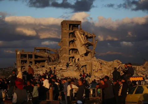 فلسطينيون قرب مبانٍ مدمرة في مخيم النصيرات بوسط قطاع غزة (أ.ف.ب)