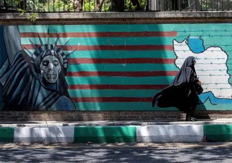 إيرانية تمر أمام جدارية معادية لواشنطن في طهران وتُظهر العلم الأميركي محاطاً بالأسلاك الشائكة وتمثال الحرية بوجه على هيئة جمجمة (أرشيفية - رويترز)