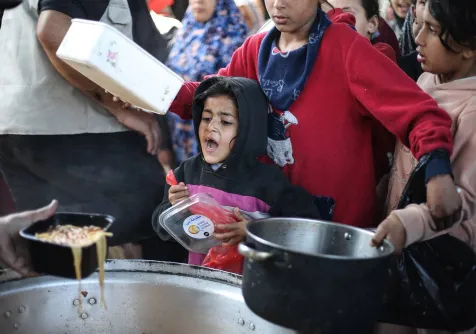 أطفال فلسطينيون نازحون يتلقون الطعام من مطبخ خيري في مخيم النصيرات للاجئين وسط قطاع غزة (أ.ف.ب)