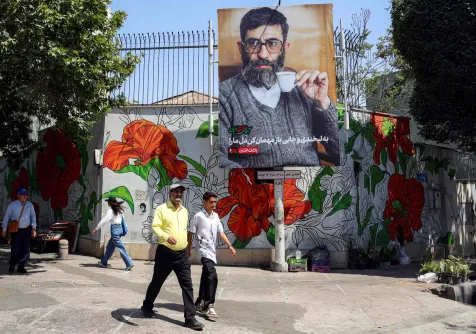 مارة أمام لوحة نعي لعلي خامنئي في طهران الثلاثاء قبل مراسم تشييعه المقررة في 4 يوليو (أ.ف.ب)