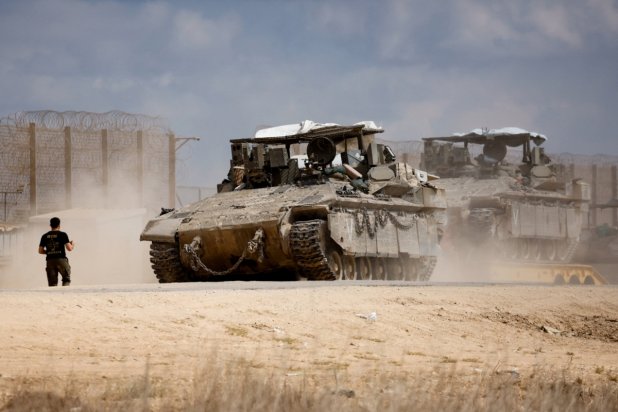 İsrail'in güneyindeki Gazze sınırında, İsrail ve Hamas arasındaki ateşkesin ardından bir İsrail askeri zırhlı personel taşıyıcısının yanında duruyor, 12 Ekim (Reuters)
