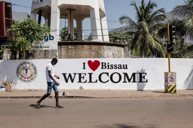 “Bissau'yu seviyorum” yazan bir duvar resminin önünden geçen bir adam, 27 Kasım 2025 (AFP)