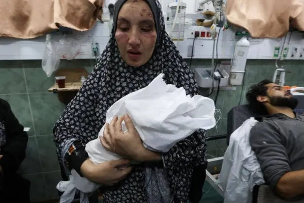 Gazze'deki bir hastanede yaralı Filistinli kadın ve kucağındaki yeni doğmuş bebeği (Reuters)