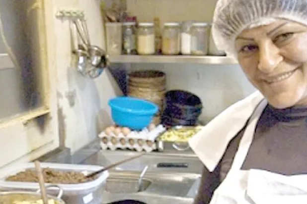 أم نزيه تعد أحد الأطباق الرئيسة للمقهى