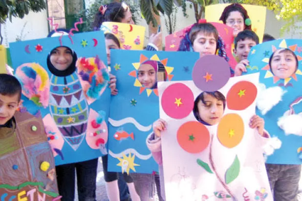 مجموعة من أطفال المحترف مع رسوماتهم