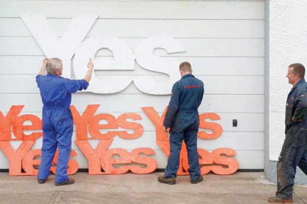 موظفون يضعون شعارات مختلفة الأحجام لحملة «نعم» المؤيدة لانفصال اسكوتلندا عند مدخل محلهم في منطقة ستورنواي التابعة لجزيرة لويس الاسكوتلندية أمس (رويترز)