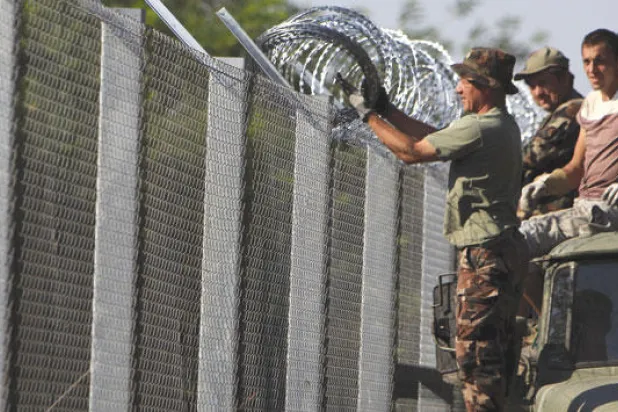 جنود مجريون يضبطون الأسلاك الشائكة فوق سور على الحدود لمنع تدفق اللاجئين الذين يشكل السوريون غالبيتهم (رويترز)