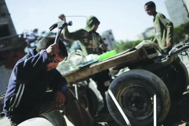 صبي يحمل مطرقة من الحديد يعمل على إصلاح كرسي معدني 