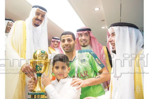 خادم الحرمين يتوج قائد الأهلي تيسير الجاسم بالكأس ويبدو رئيس النادي مساعد الزويهري (تصوير: بندر الجلعود)
